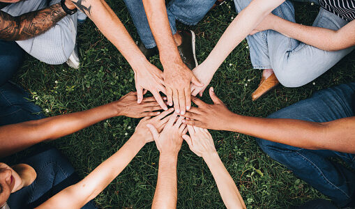 People stacking hands together in the park